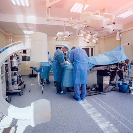 Surgeons in full PPE and shoe covers in an operating room.