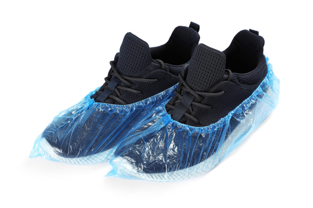 Pair of black sneakers in medical blue covers on white background.