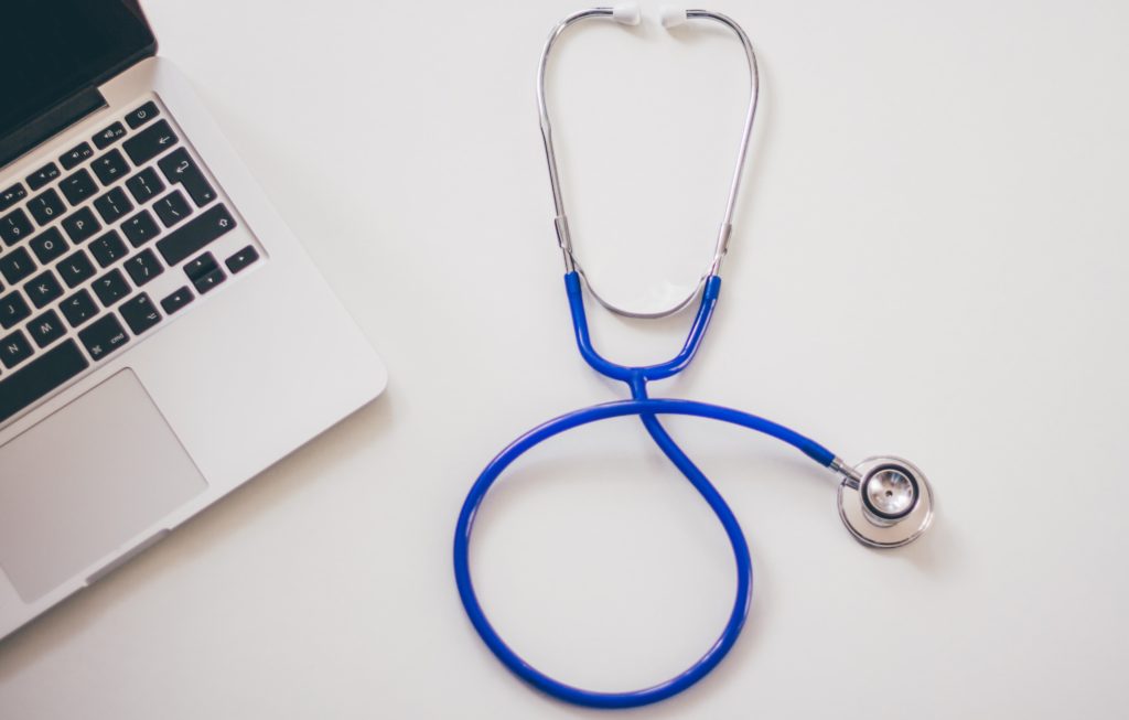 Stethoscope and laptop on a desk at medical office.