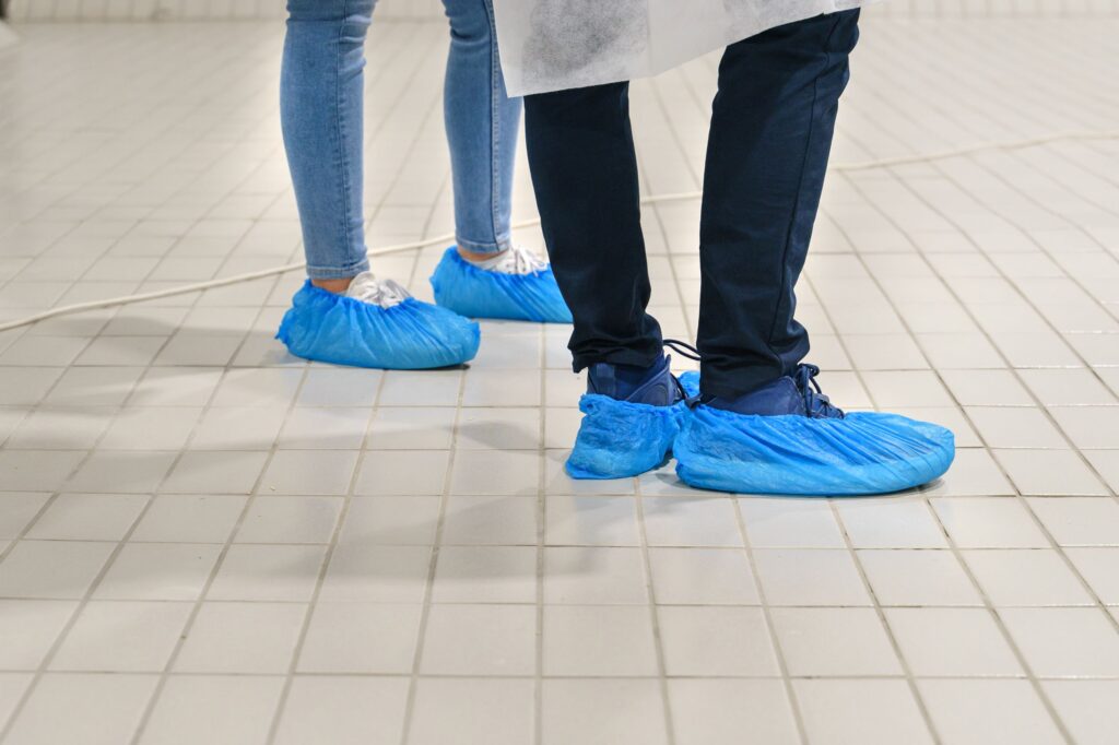 Two people wearing blue shoe covers at a hospital.