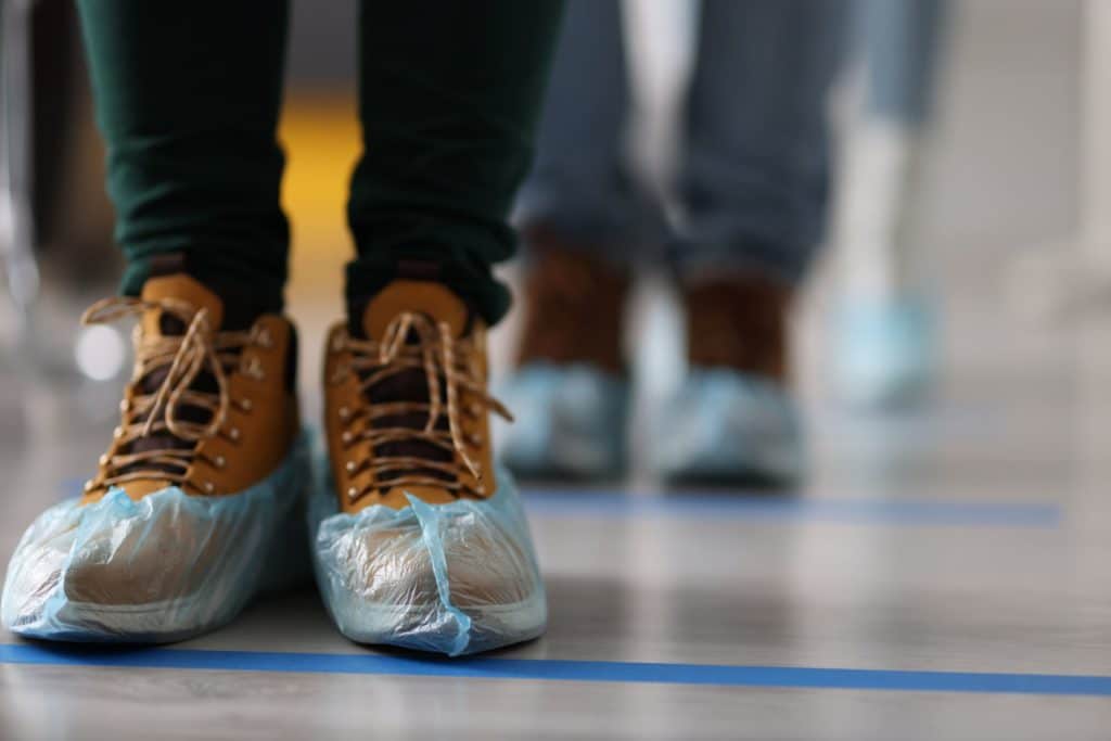 Standing person wearing protective shoe covers on their boots.