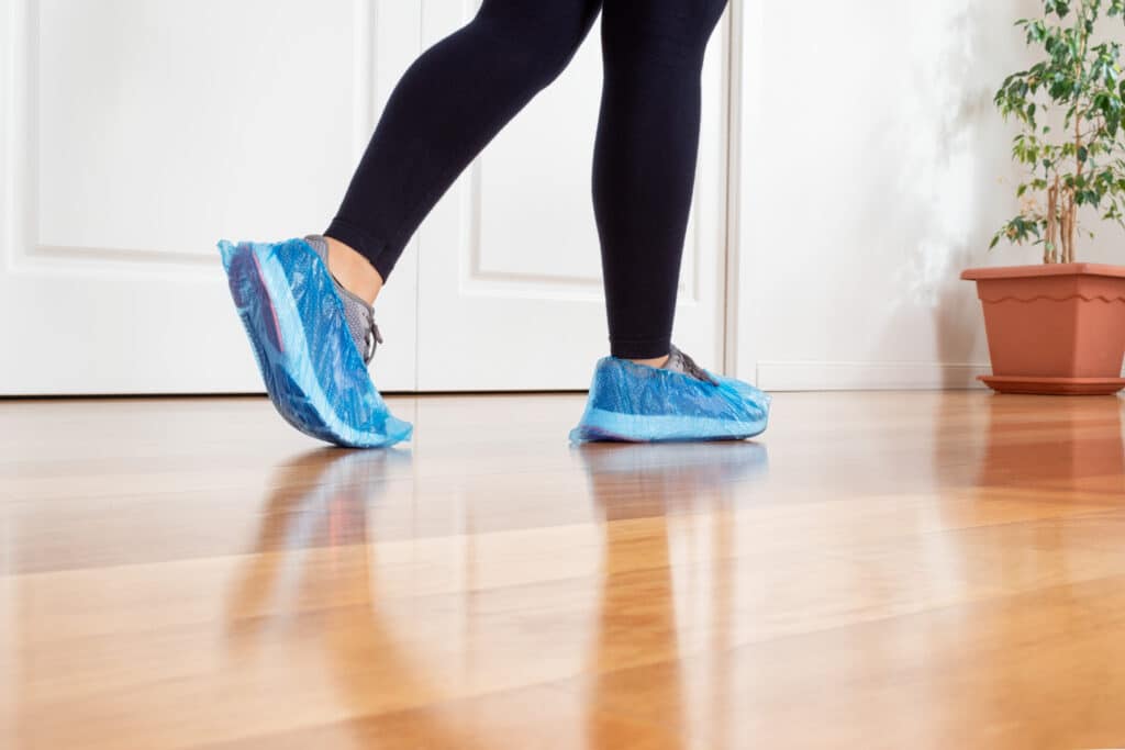 Woman wearing shoe covers while cleaning her home